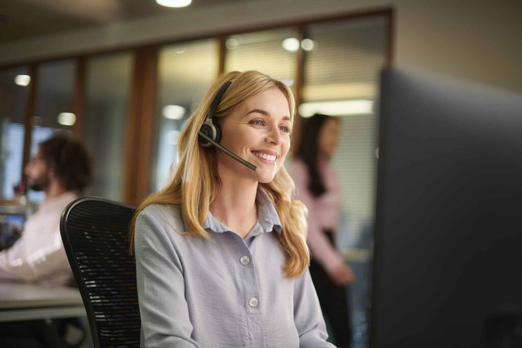 Friendly customer service agent on headset having a warm conversation with a client, building trust and delivering professional telemarketing support.